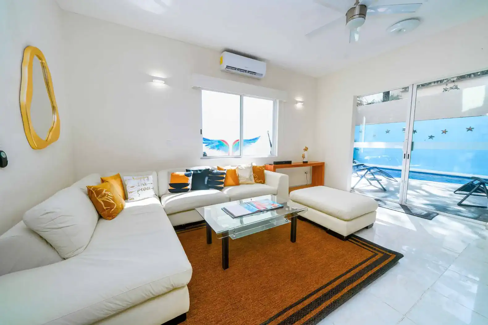 Bright living room with white sectional sofa and view of the private pool