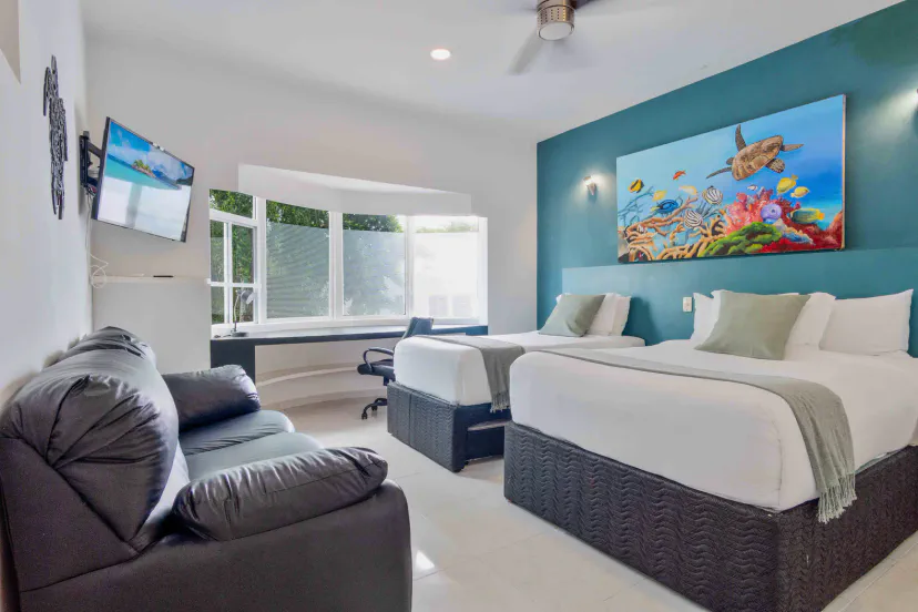 Bright double-queen room with bay window, sofa, and coastal style