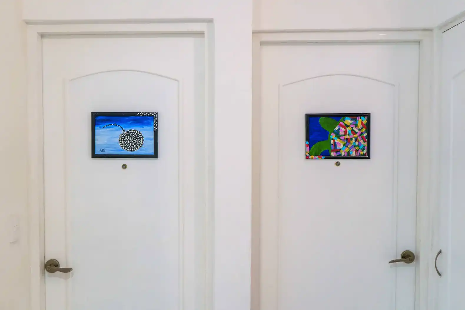 Two closed doors with framed artwork above each door