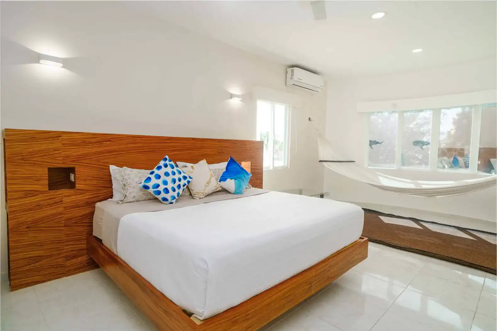 Bright and airy master bedroom with a wooden bed and colorful pillows