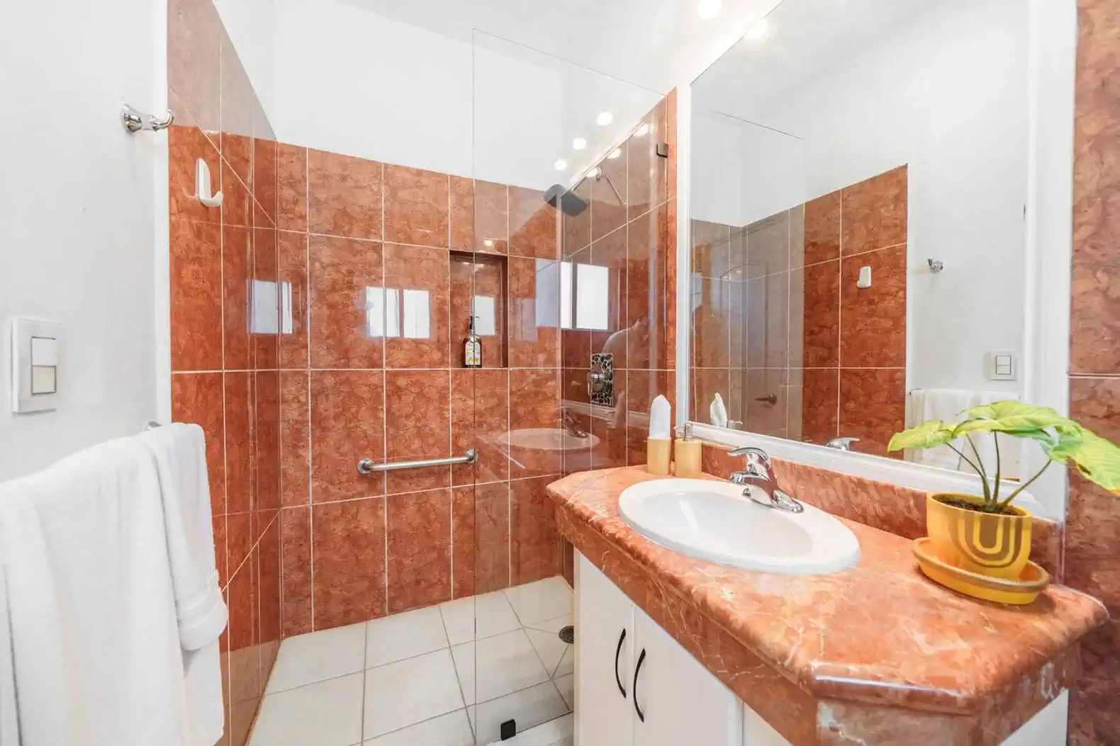 Modern bathroom featuring marble countertops and a glass shower enclosure