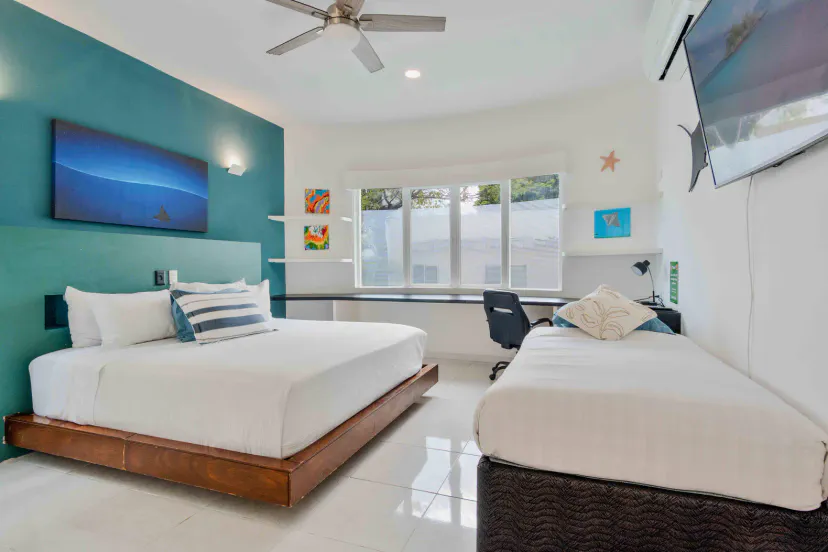 Bright modern bedroom with queen + twin beds, desk, and wall-mounted TV