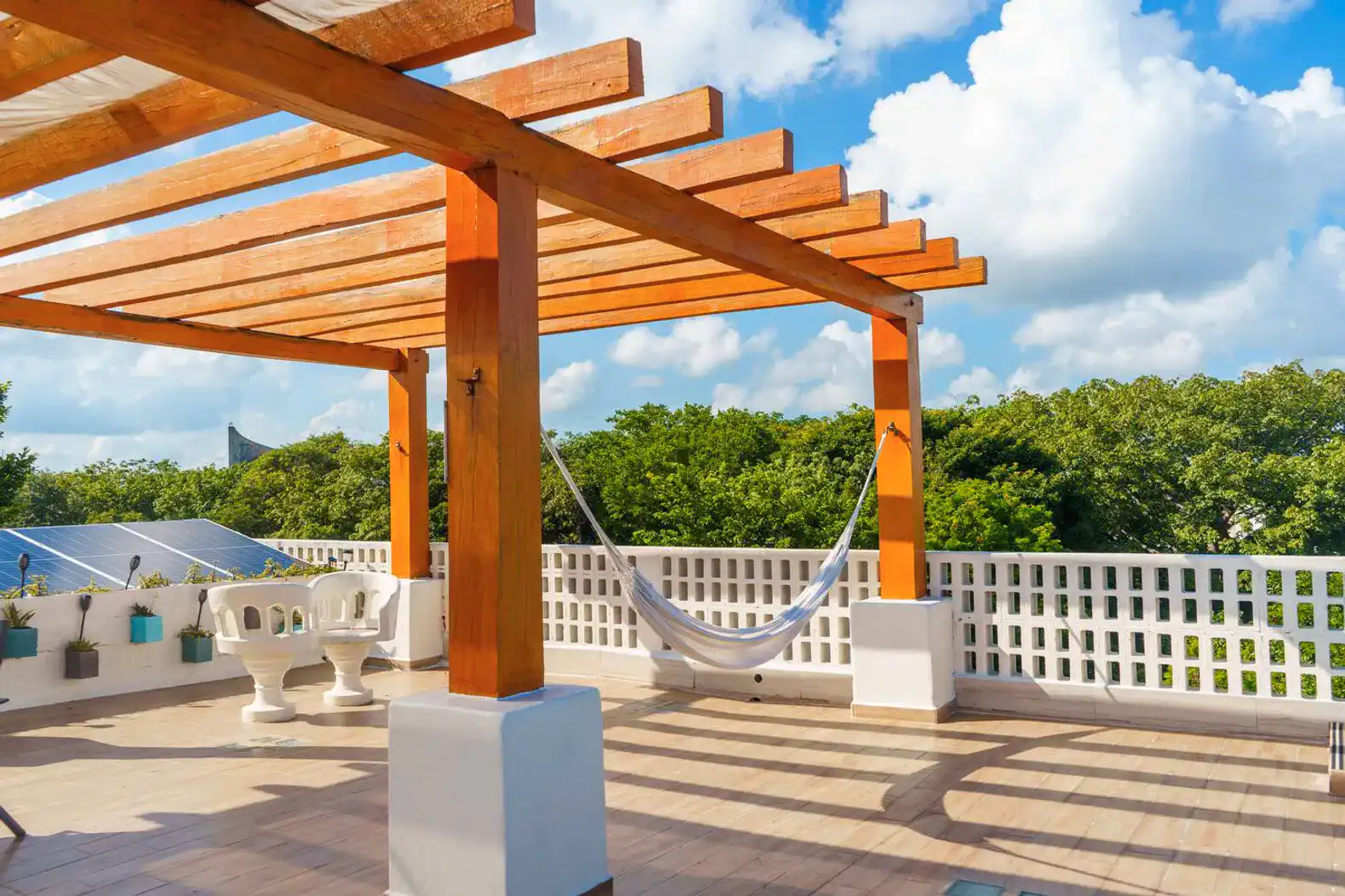 Spacious outdoor terrace with wooden pergola and hammock overlooking lush greenery