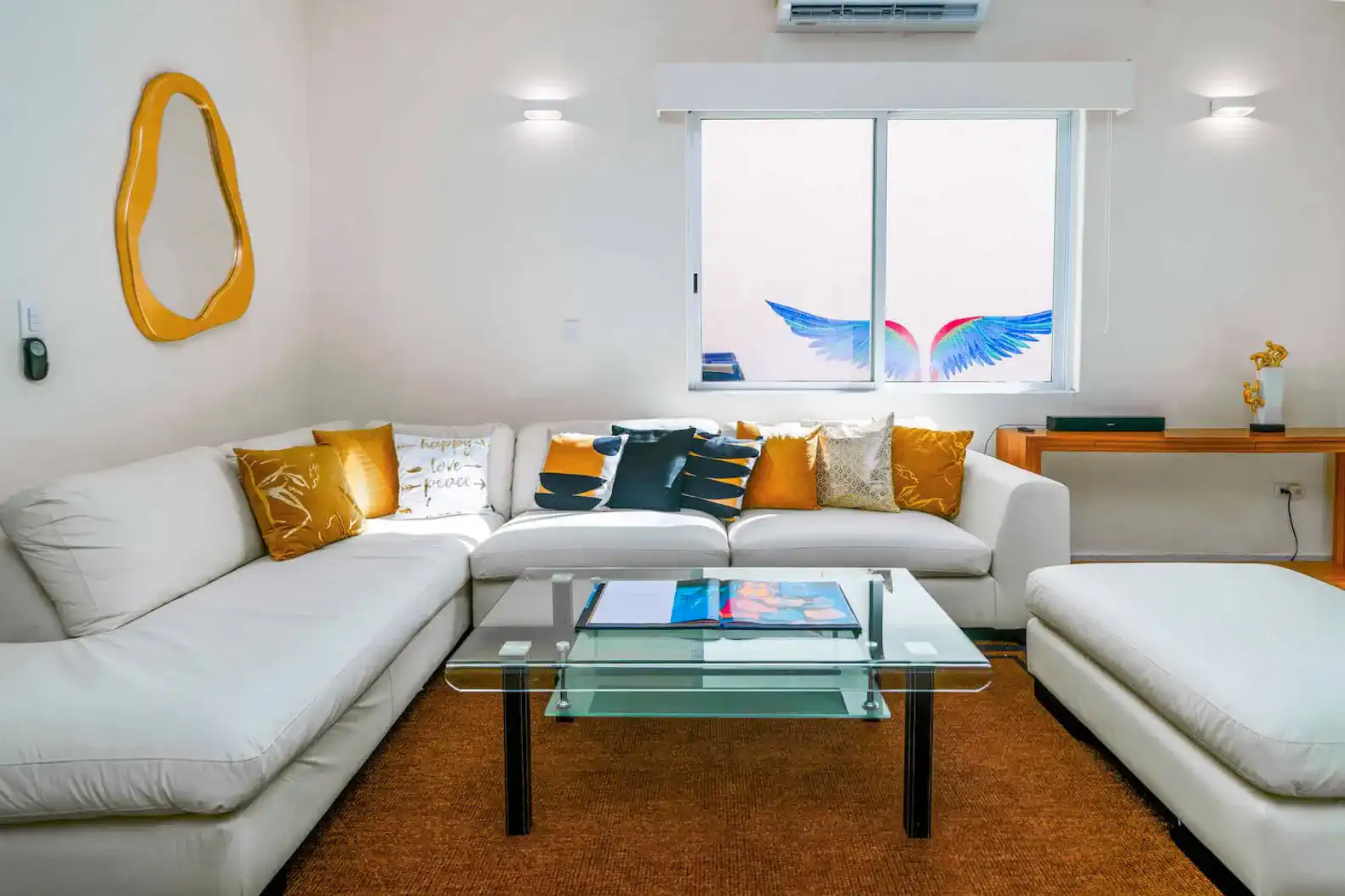 Cozy living room with white sofas, colorful cushions, and a glass coffee table