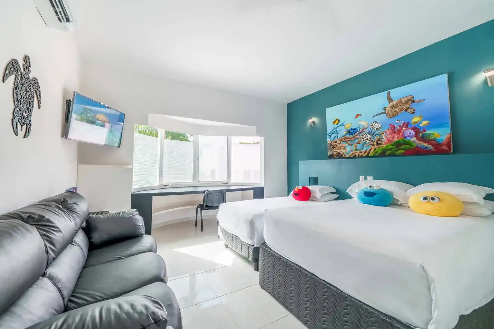 Bright guest bedroom with two beds, colorful pillows, and a large window