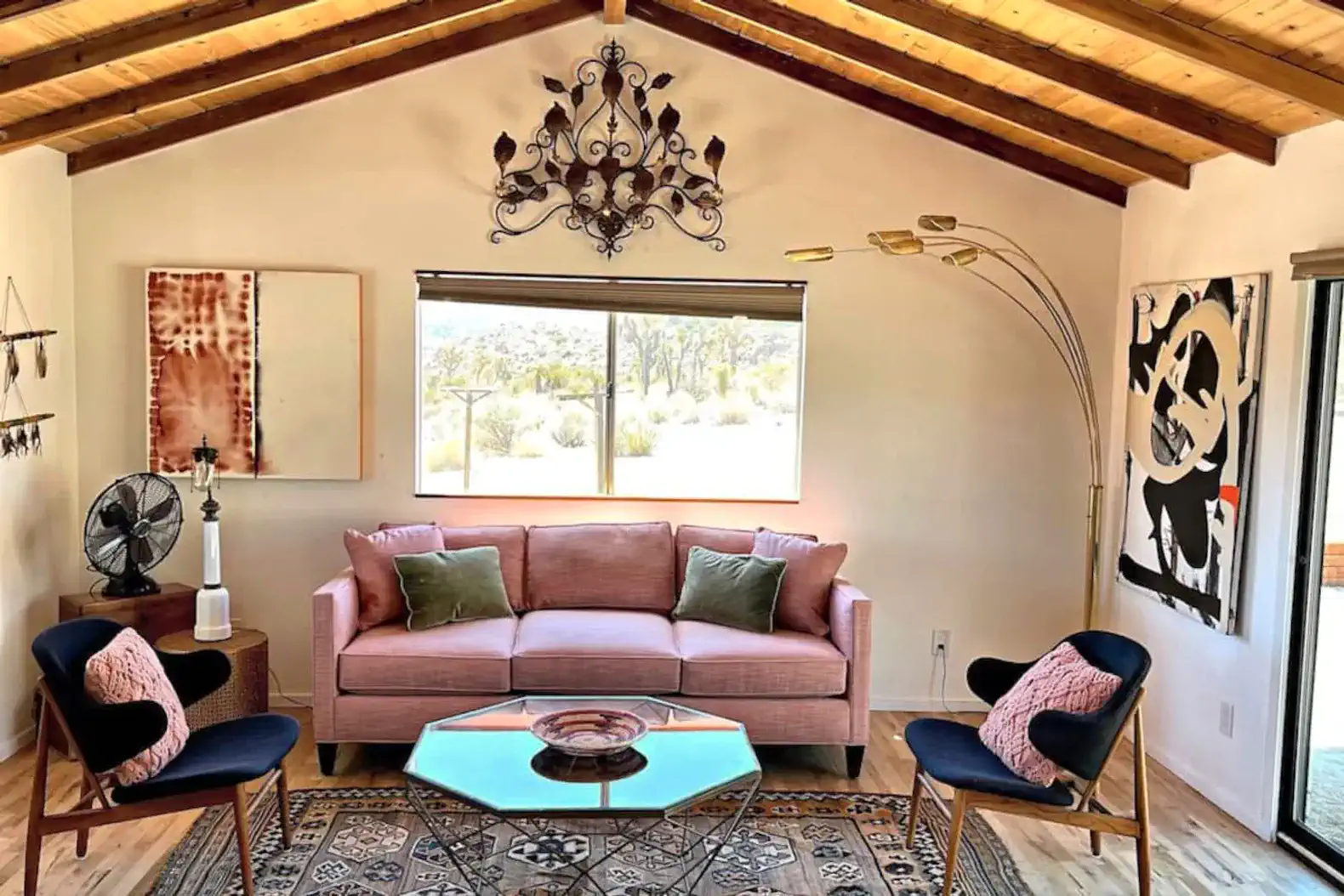 Cozy living room with pink sofa, modern decor, and large window showcasing desert views