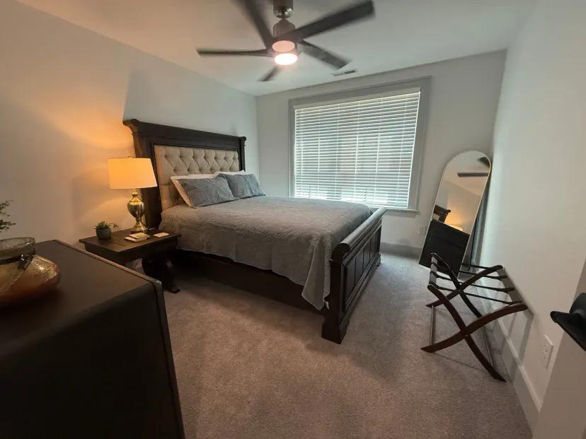 Queen size bed, luggage rack, walk in closet, ceiling fan, storage cabinet, large window overlooking the front yard, carpet, floor length mirror