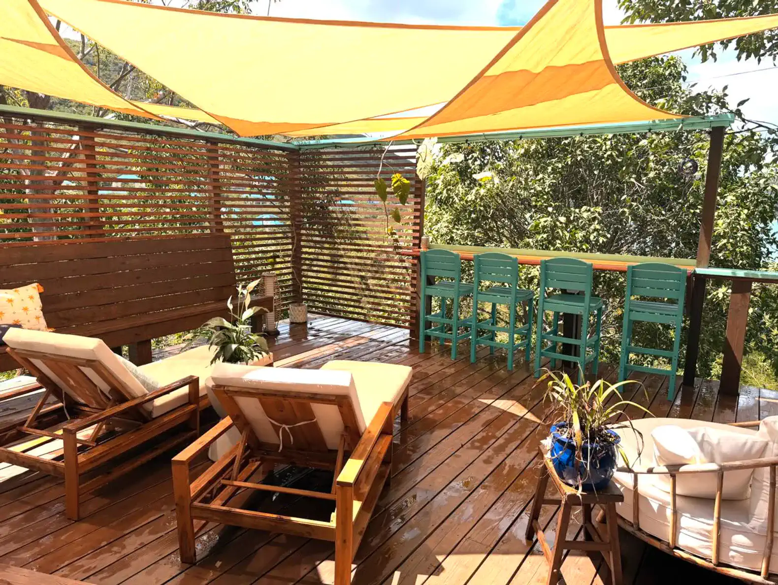 Outdoor seating area with lounge chairs and bar stools under colorful canopies