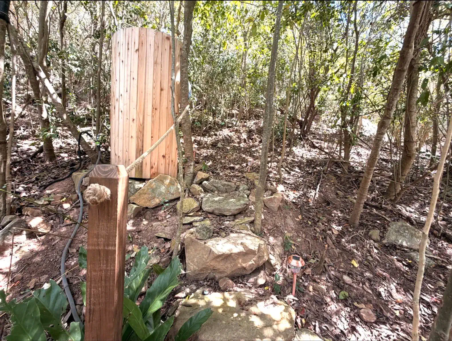 Outdoor shower surrounded by lush greenery and natural stone path
