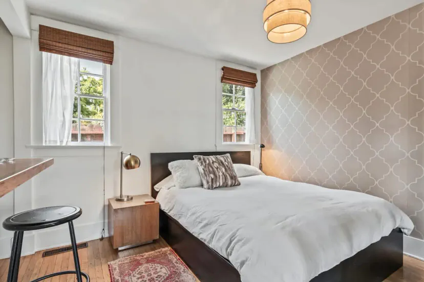 Cozy bedroom with a queen bed, stylish decor, and natural light from windows