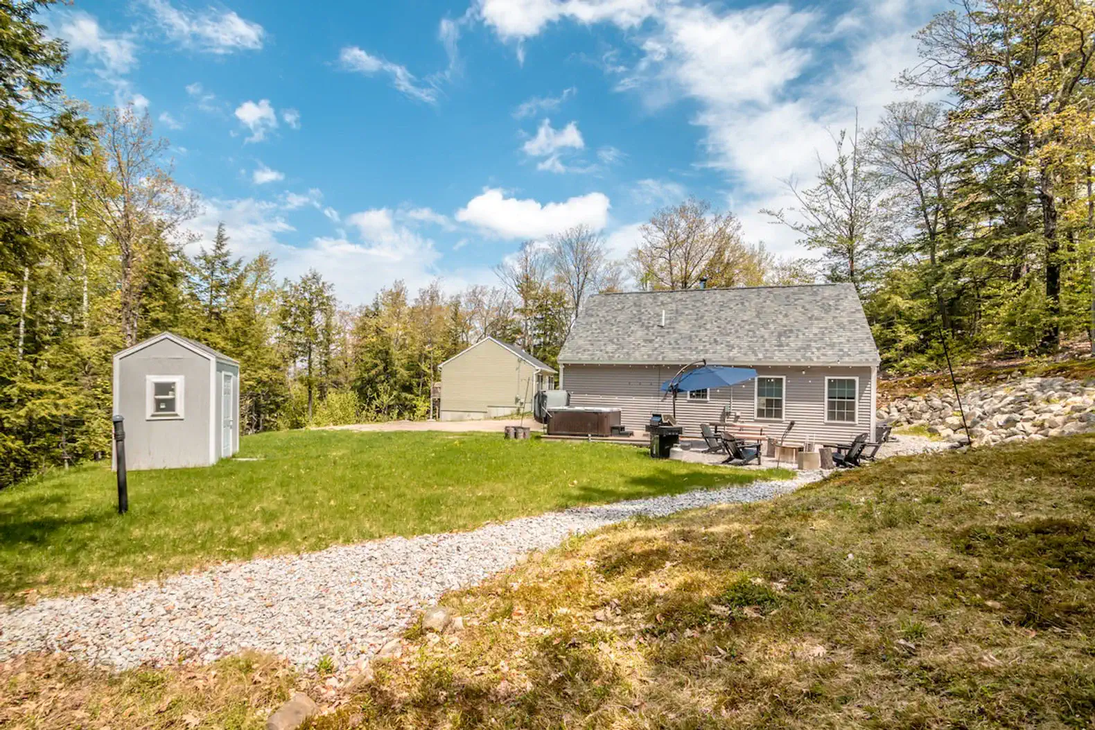 Spacious yard with a shed, seating area, and hot tub surrounded by trees