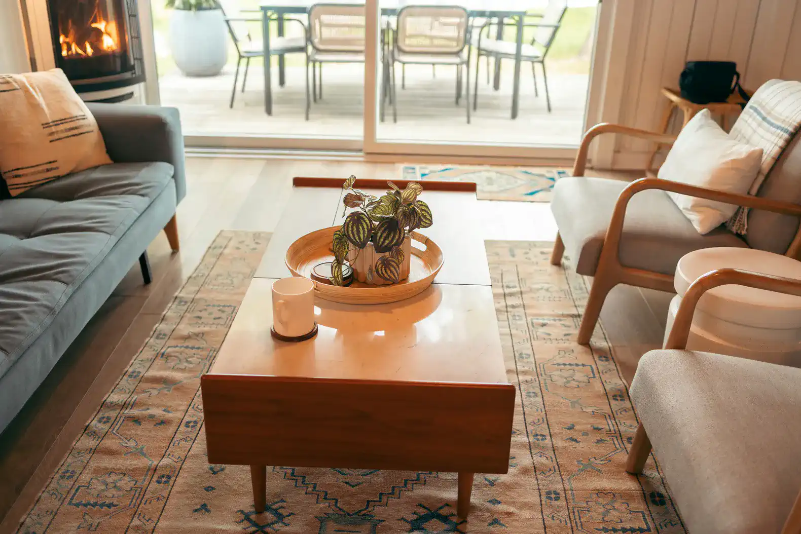 Cozy living room with a fireplace, modern furniture, and a view of the outdoor seating area
