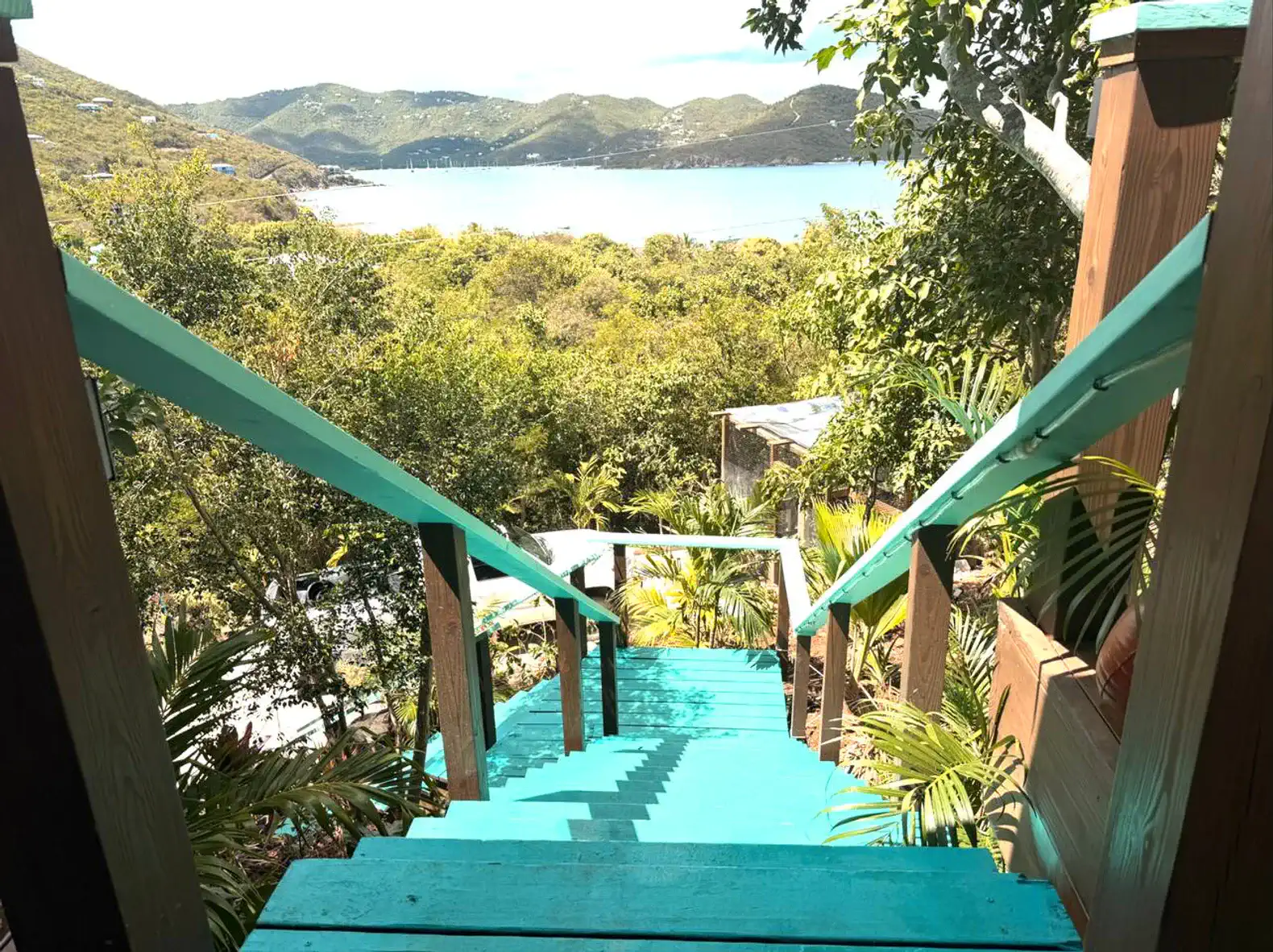 Colorful steps leading down to a lush garden with a view of the ocean and hills
