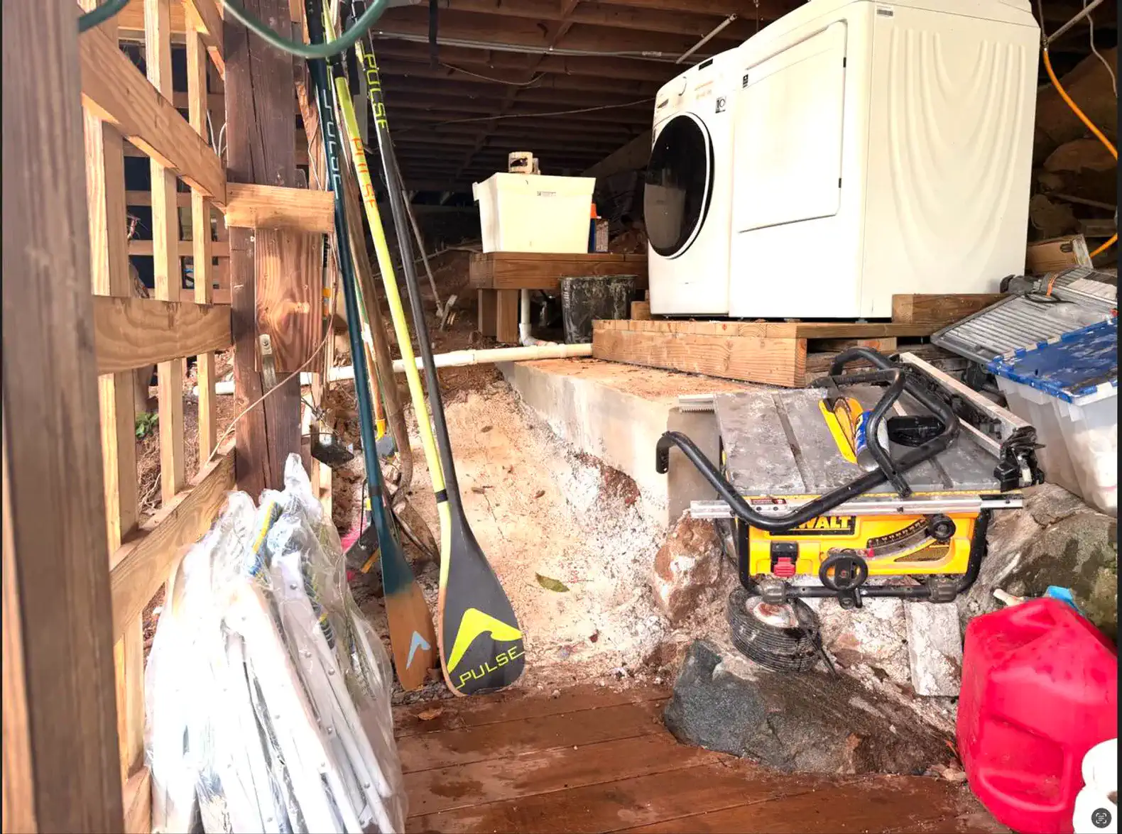 Laundry area with washing machine, paddle boards, and tools in a storage space
