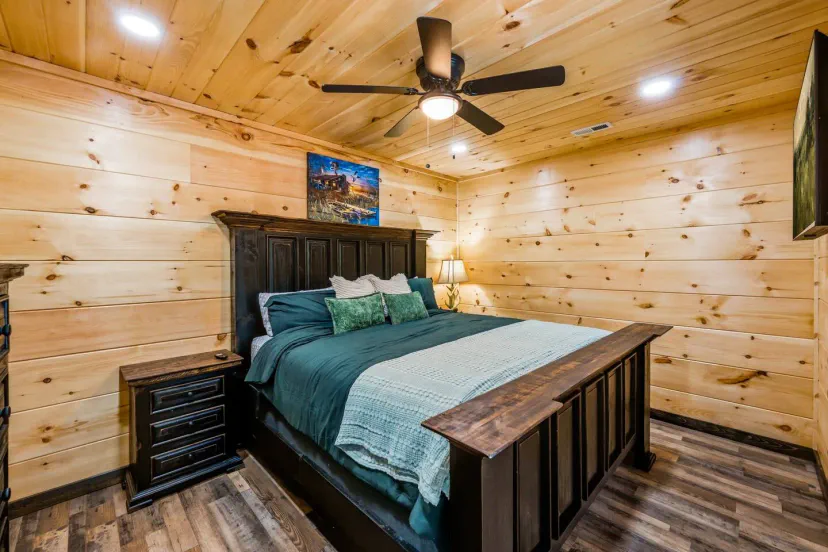 Cozy master bedroom with wooden walls and a king-size bed featuring decorative pillows