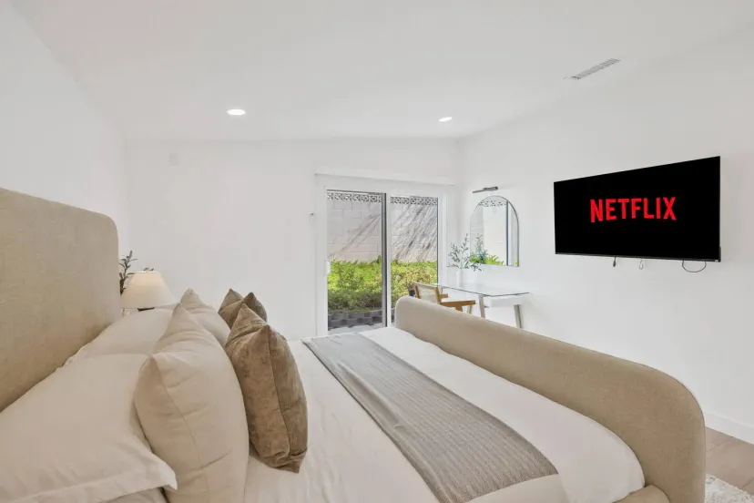 Dormitorio principal acogedor con una cama grande, televisor y acceso a área exterior