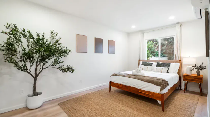 Gemütliches Schlafzimmer mit einem komfortablen Bett, dekorativer Kunst und natürlichem Licht von einem Fenster