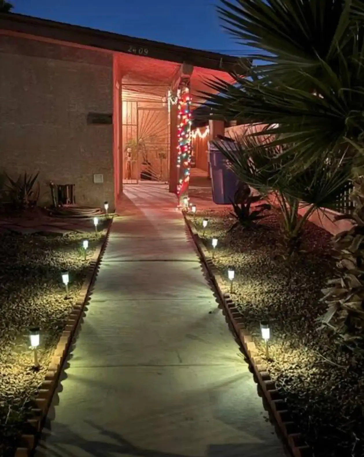Illuminated pathway leading to the entrance with decorative lights