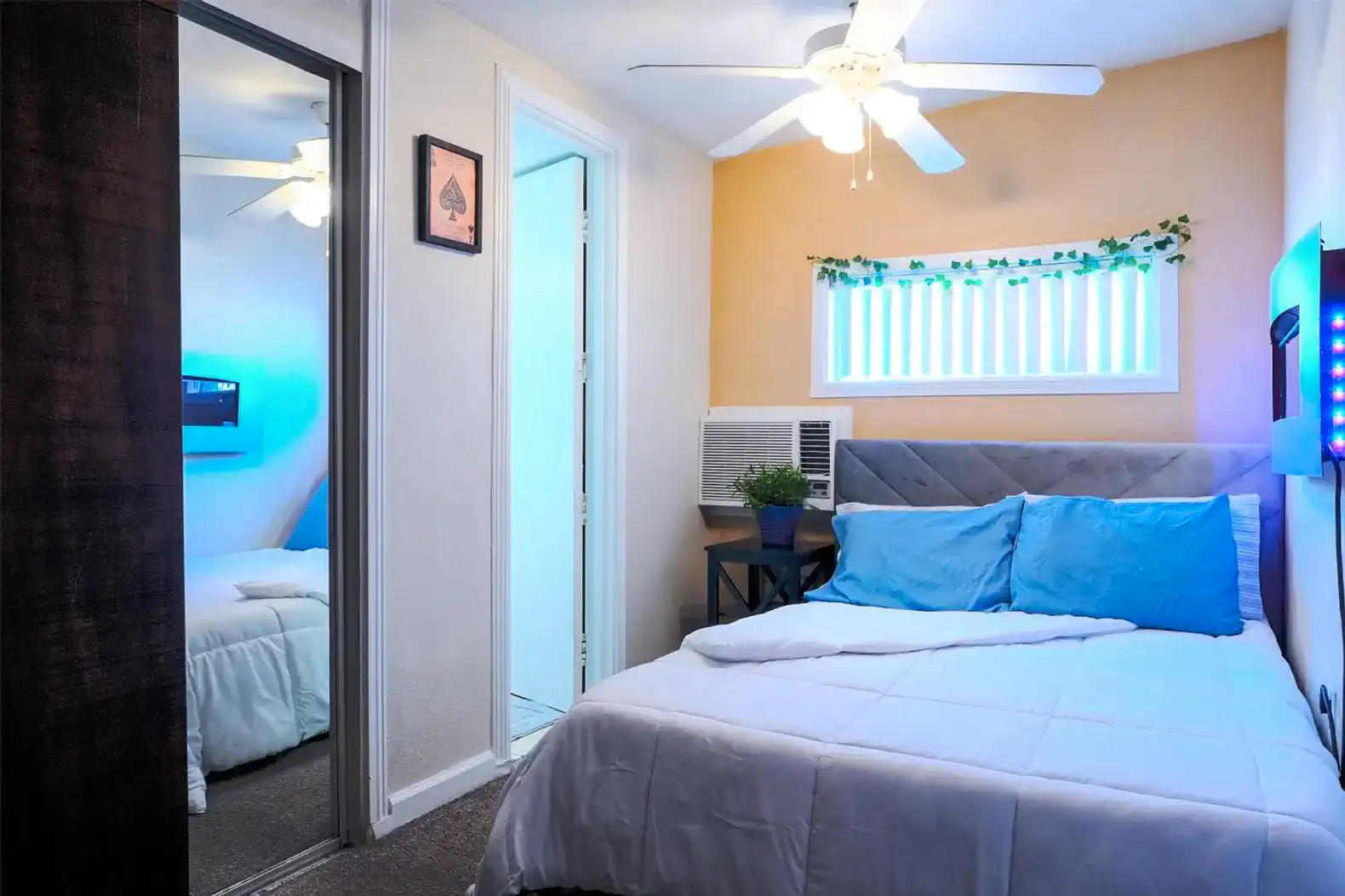 Cozy bedroom with a queen bed, ceiling fan, and wall-mounted TV