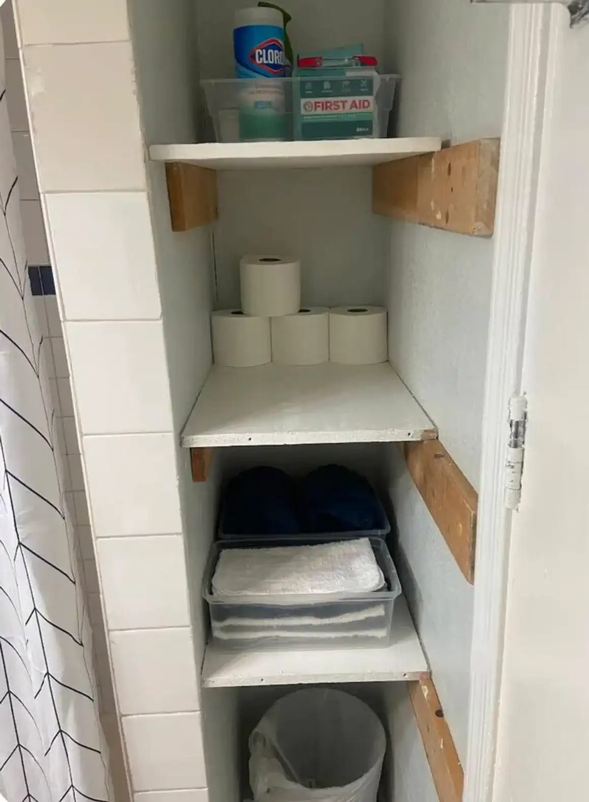 Storage shelves with towels, toilet paper, and first aid supplies
