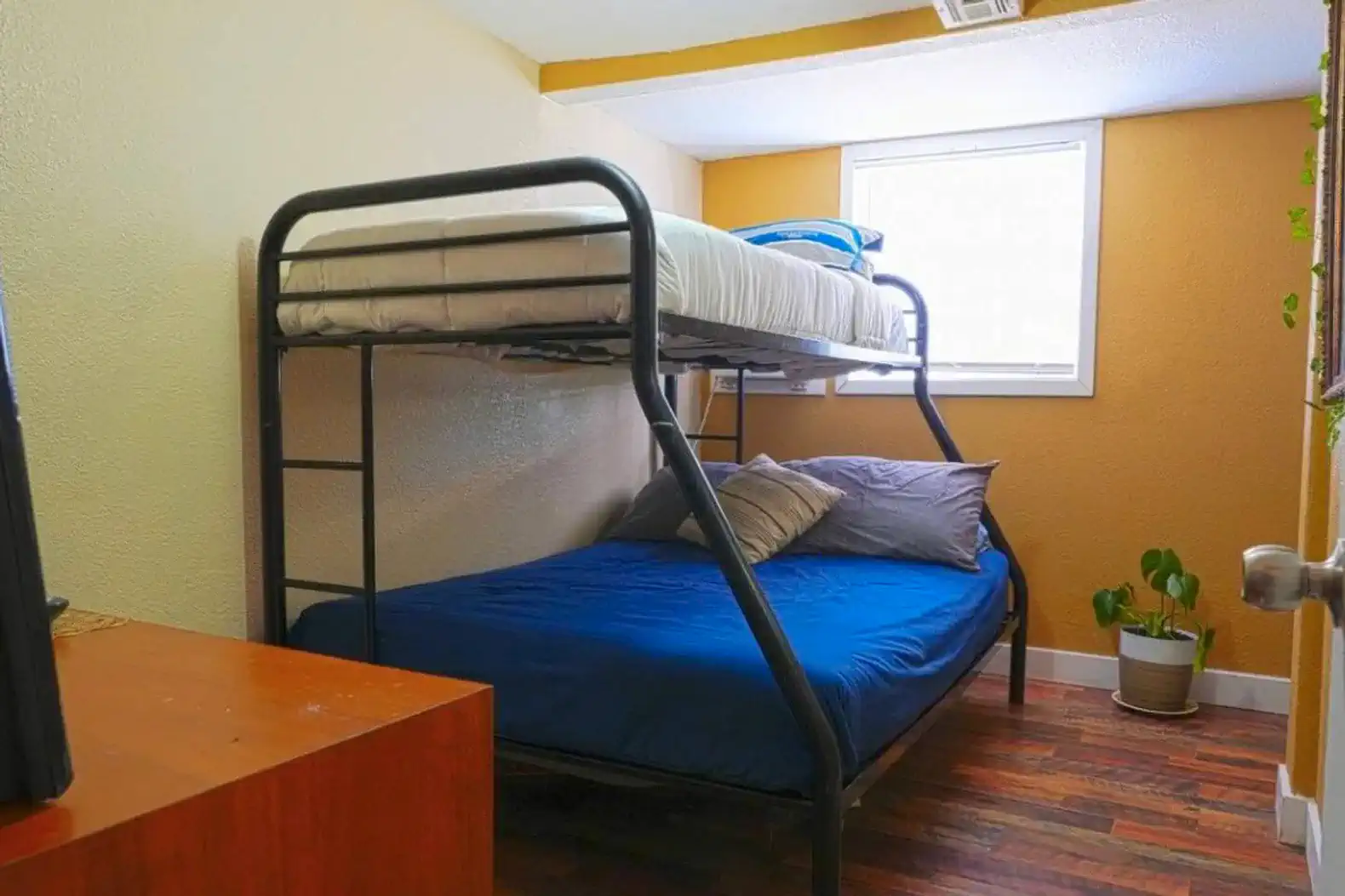 Cozy bunk room with a bunk bed and a double bed, featuring warm tones and natural light
