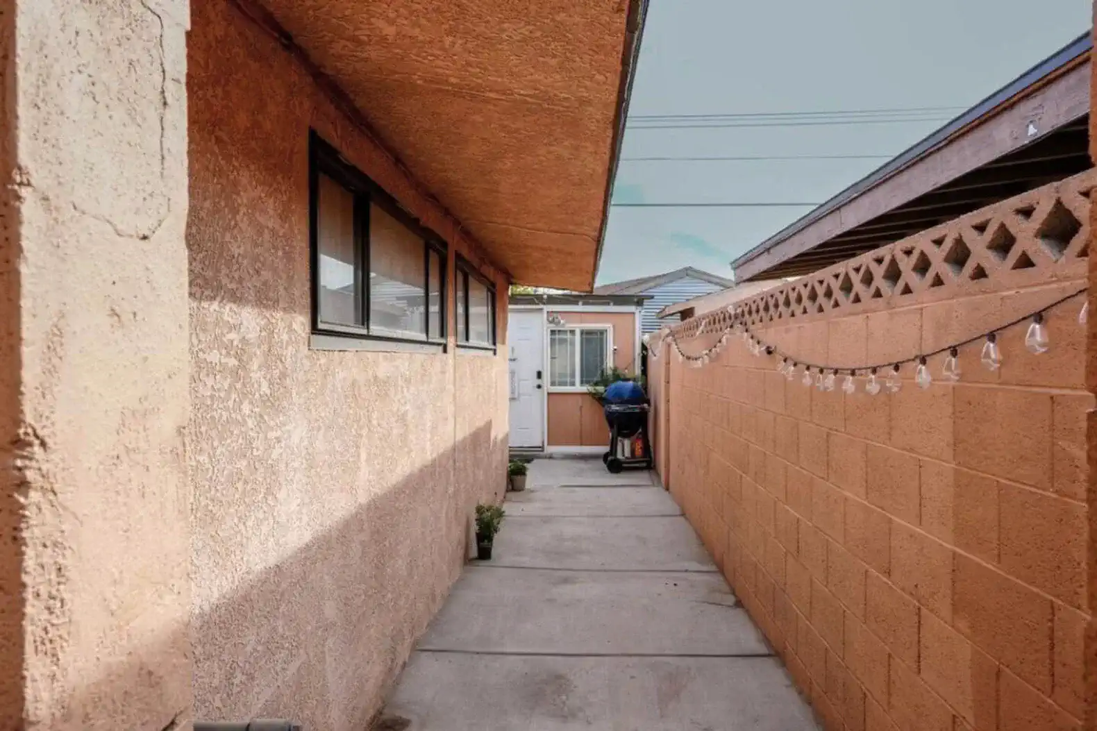 Narrow walkway leading to a door with decorative lights along the wall