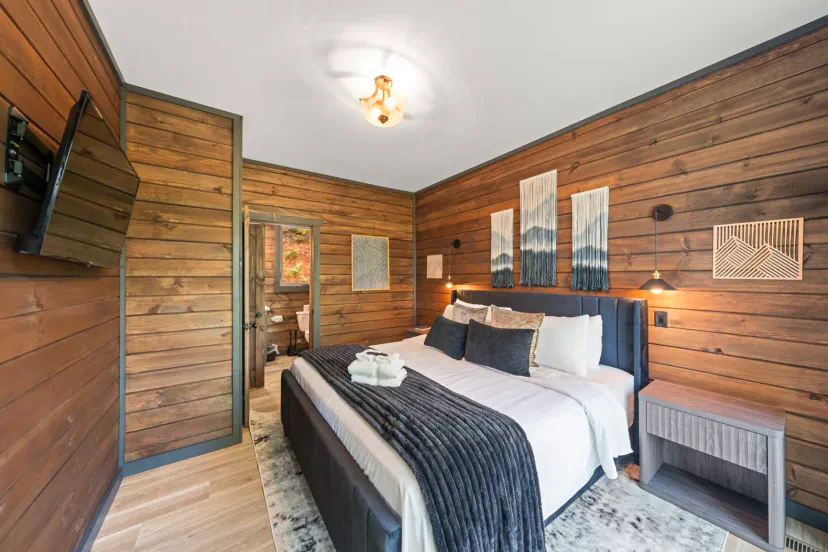 Chambre principale confortable avec des murs en bois, une literie moelleuse et une décoration moderne