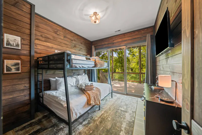 Chambre à lits superposés confortable avec un lit double et des lits superposés simples, grandes fenêtres donnant sur les arbres