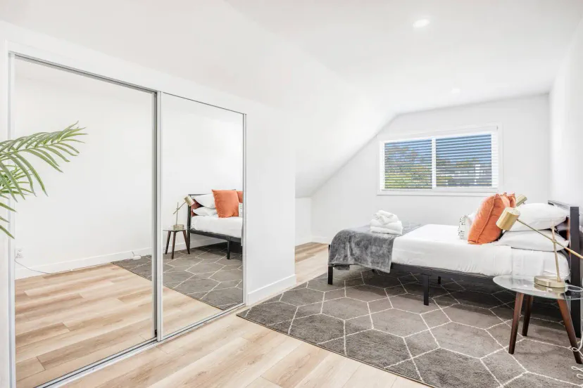 Acogedor dormitorio de invitados con una cama, almohadas decorativas y armario con espejo