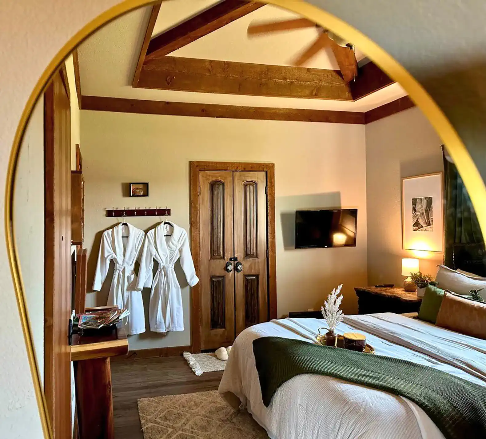 Cozy master bedroom with wooden beams, a TV, and plush bedding