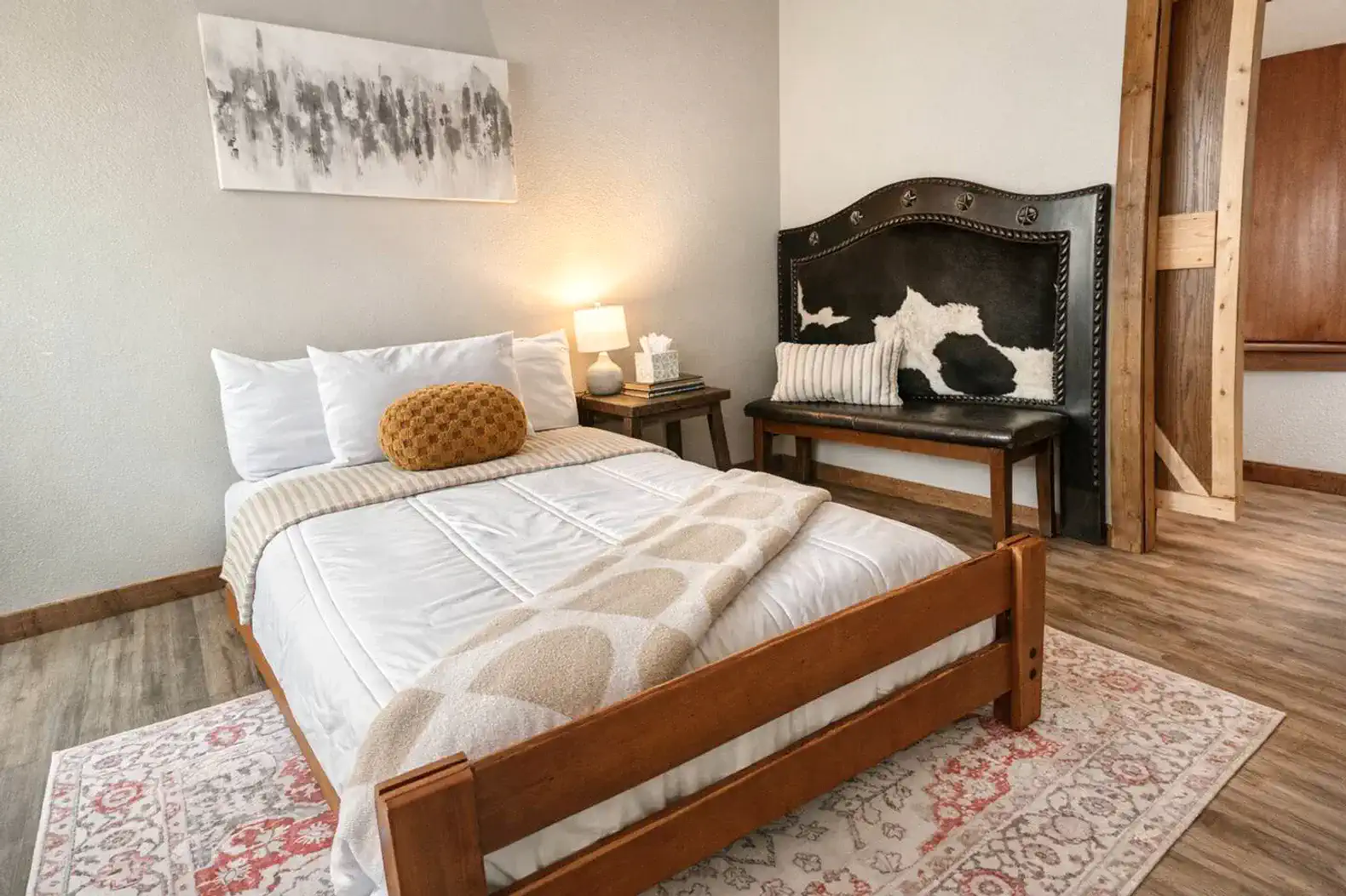 Cozy guest bedroom with a wooden bed, decorative pillows, and a unique cowhide bench