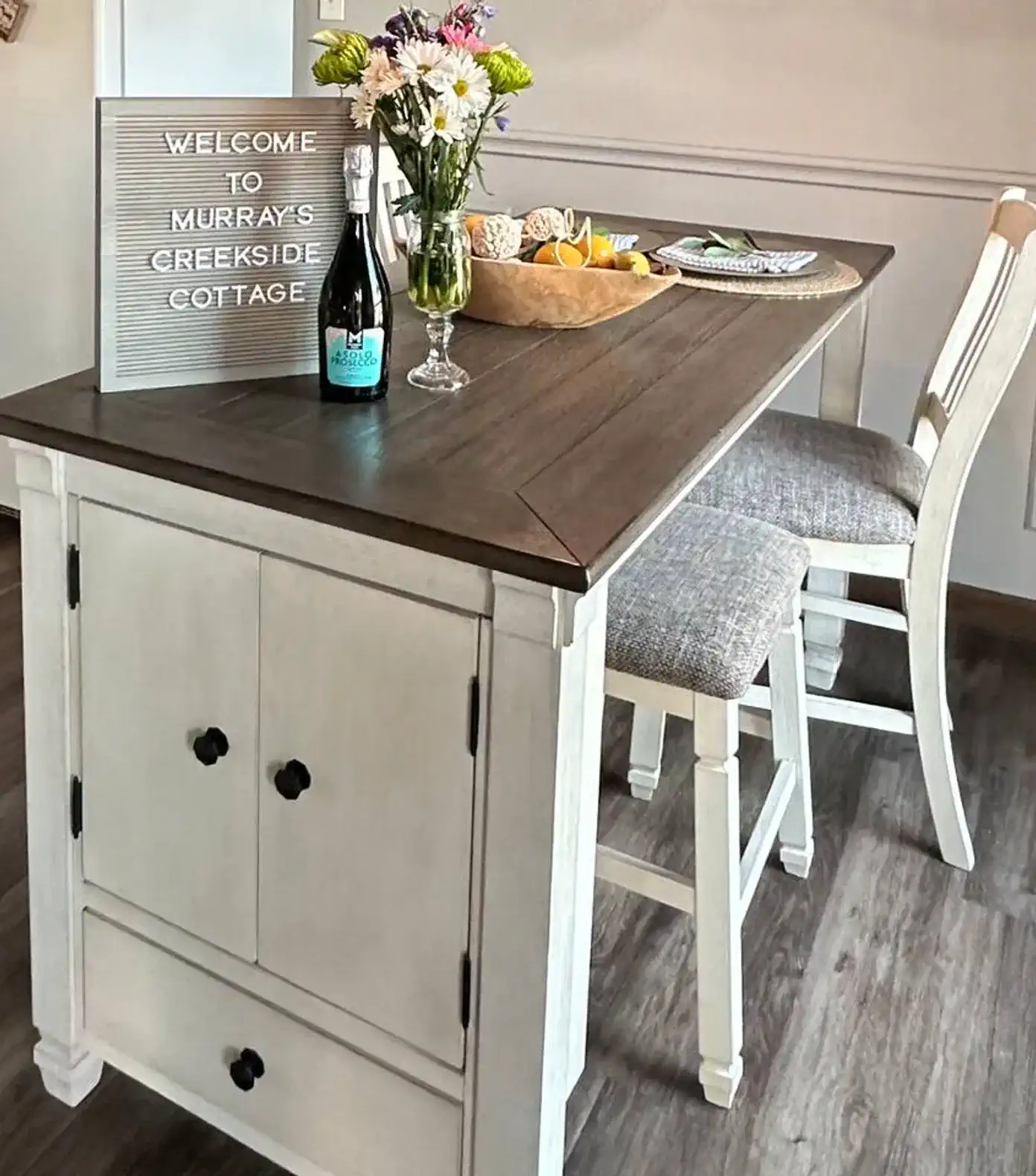 Cozy dining area with a wooden table, flowers, and a welcome sign