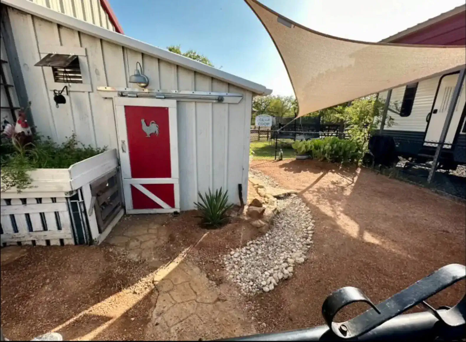 Charming entrance with a red door, gravel path, and shaded outdoor area
