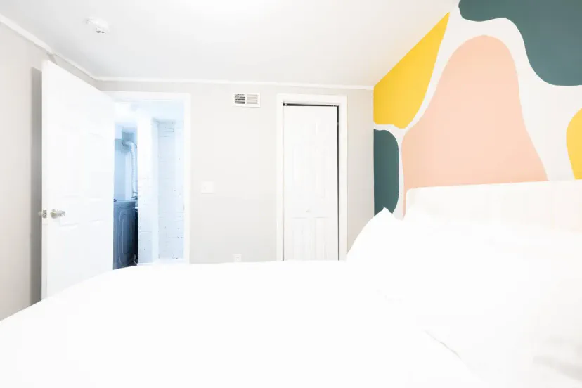 Brightly colored accent wall in a cozy bedroom with a view of the bathroom door