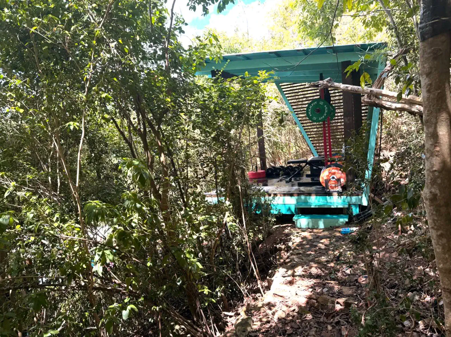 Área externa coberta cercada por vegetação, ideal para relaxar em meio à natureza