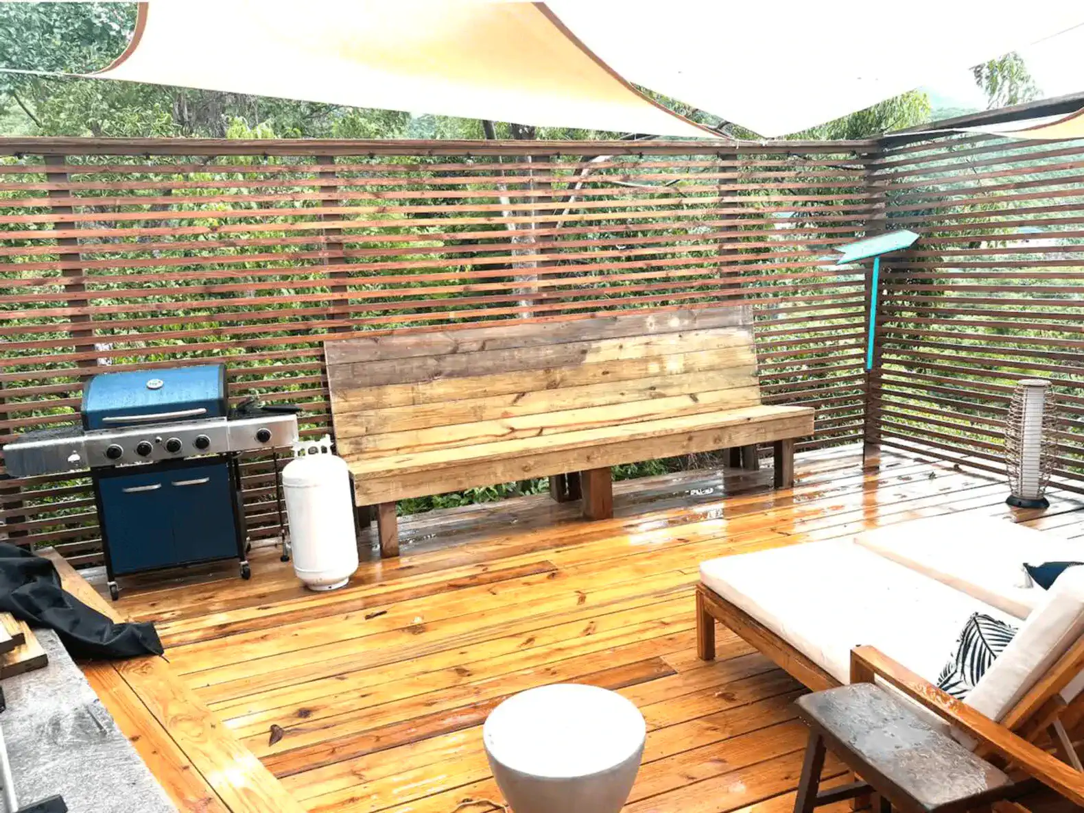 Outdoor seating area with wooden bench and BBQ grill under shade