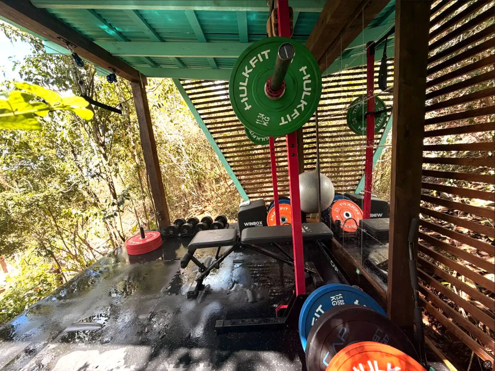 Espaço de treino ao ar livre com equipamentos de musculação e pesos coloridos