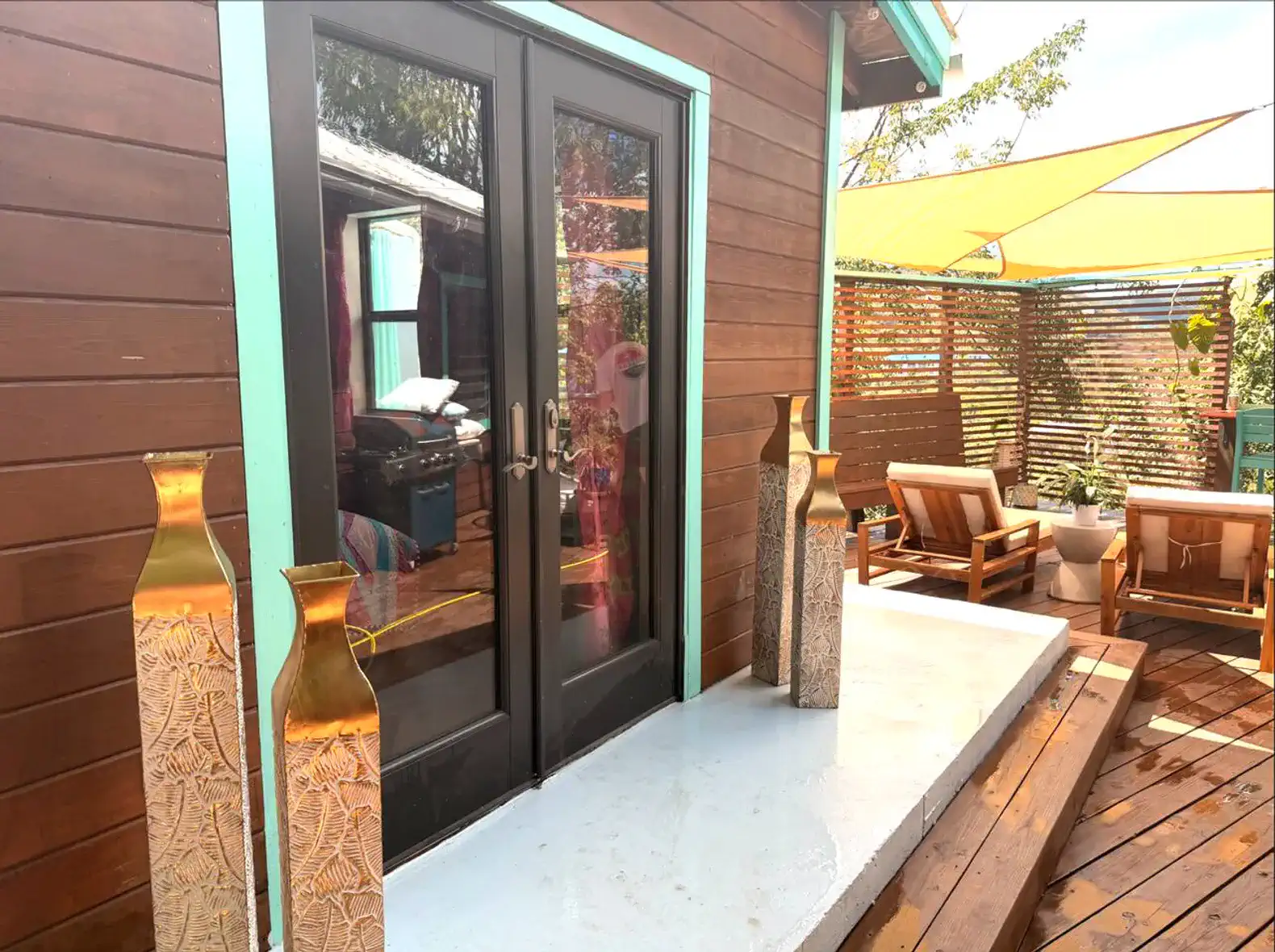 Entrada com portas de vidro, vasos decorativos e área de estar ao ar livre