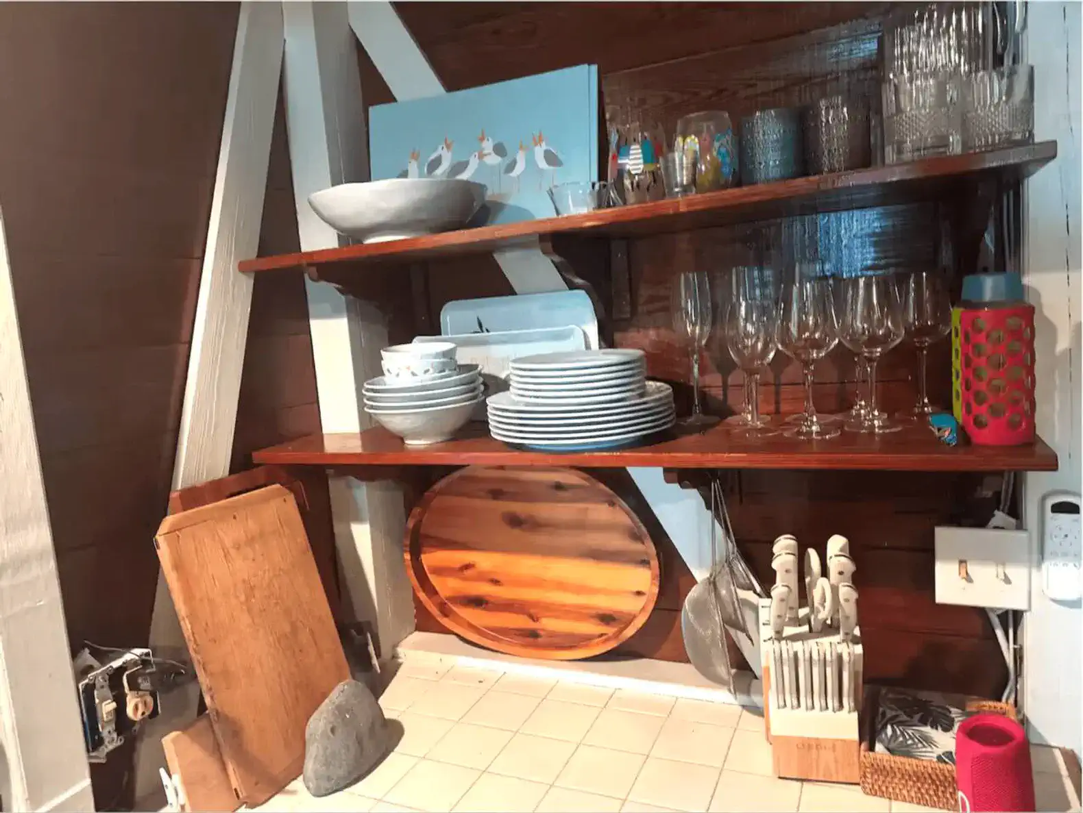 Wooden shelves filled with dishes, glassware, and kitchen utensils