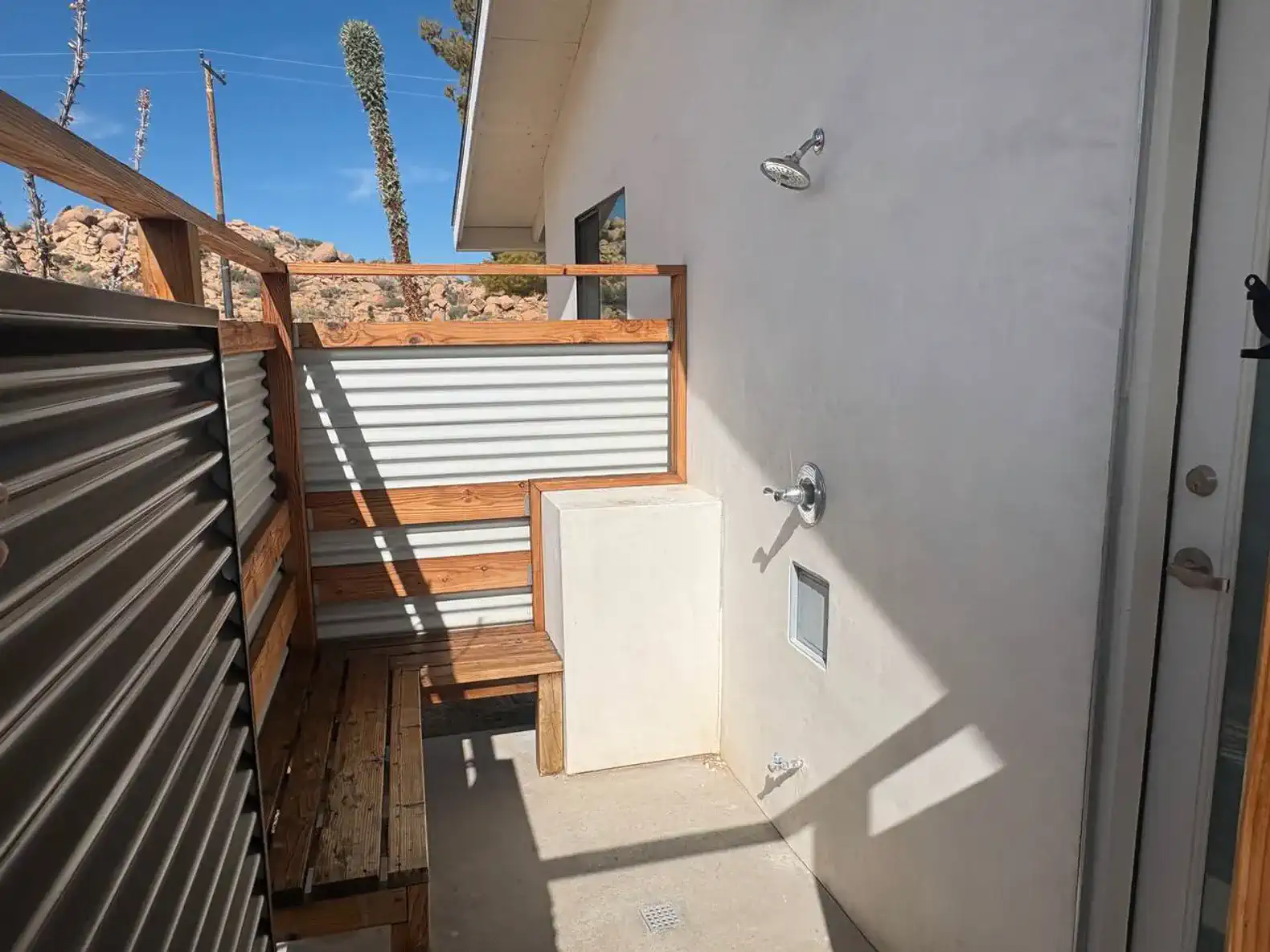 Outdoor shower area with wooden seating and privacy screens