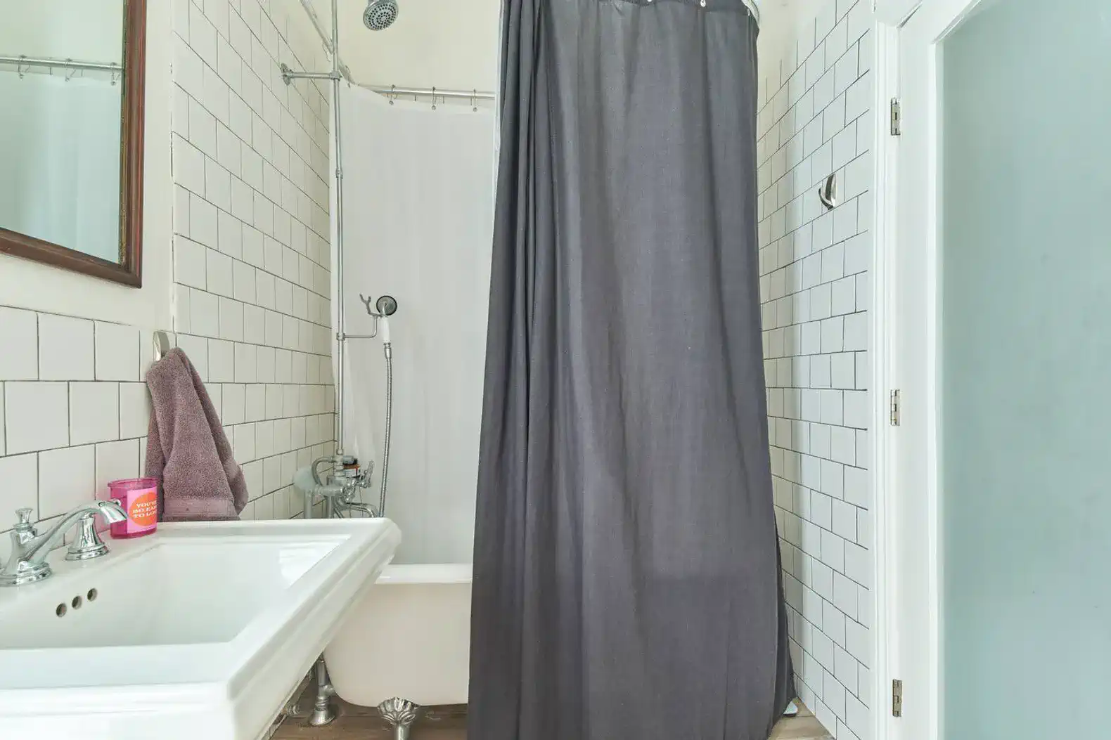 Compact bathroom featuring a shower curtain, bathtub, and sink with tiled walls