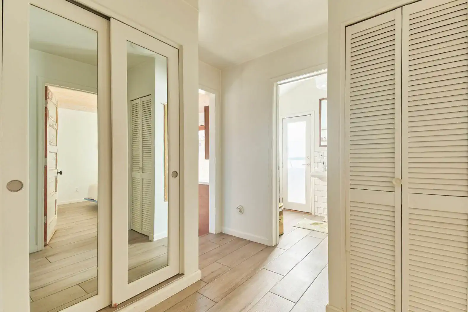 Bright hallway with mirrored closet doors and light wood flooring