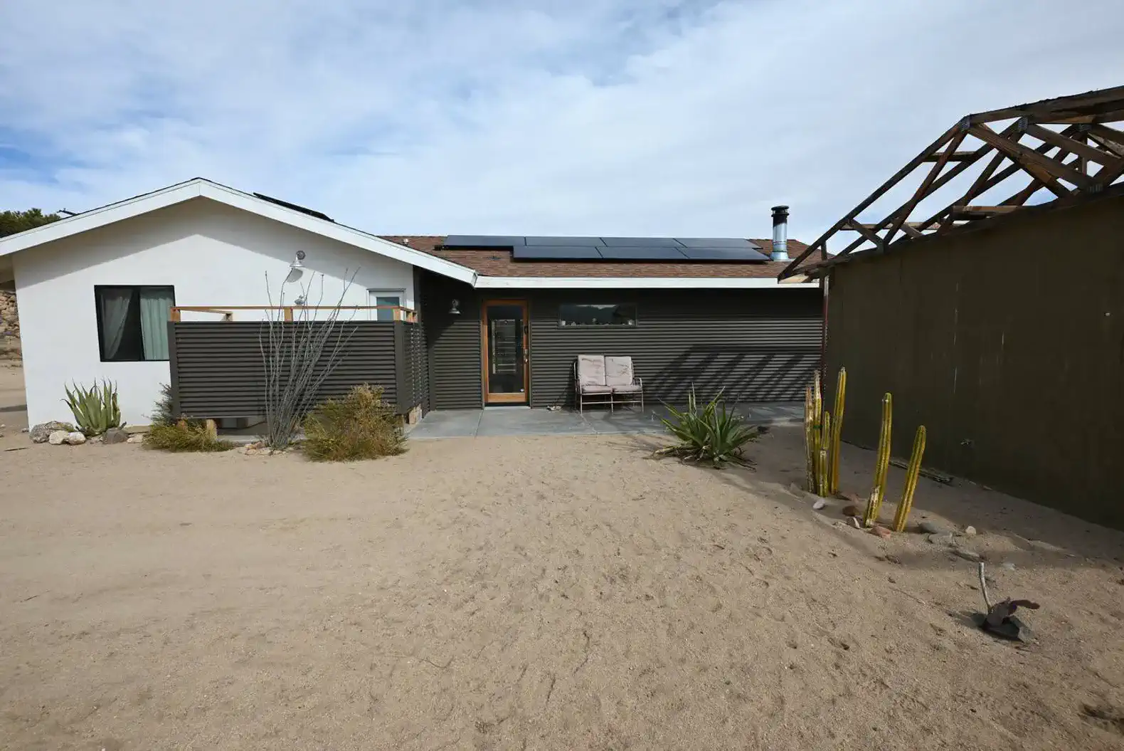 Desert landscape with a modern home featuring solar panels and outdoor seating