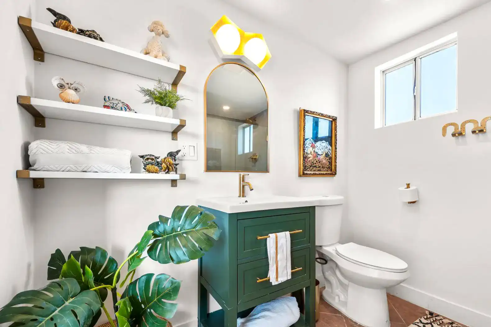 Bright bathroom featuring a green vanity, decorative shelves, and modern fixtures
