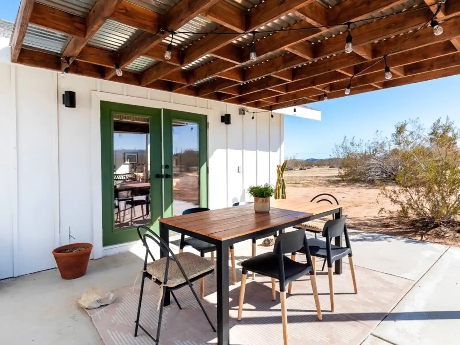 Outdoor dining area with a wooden table and chairs under a pergola