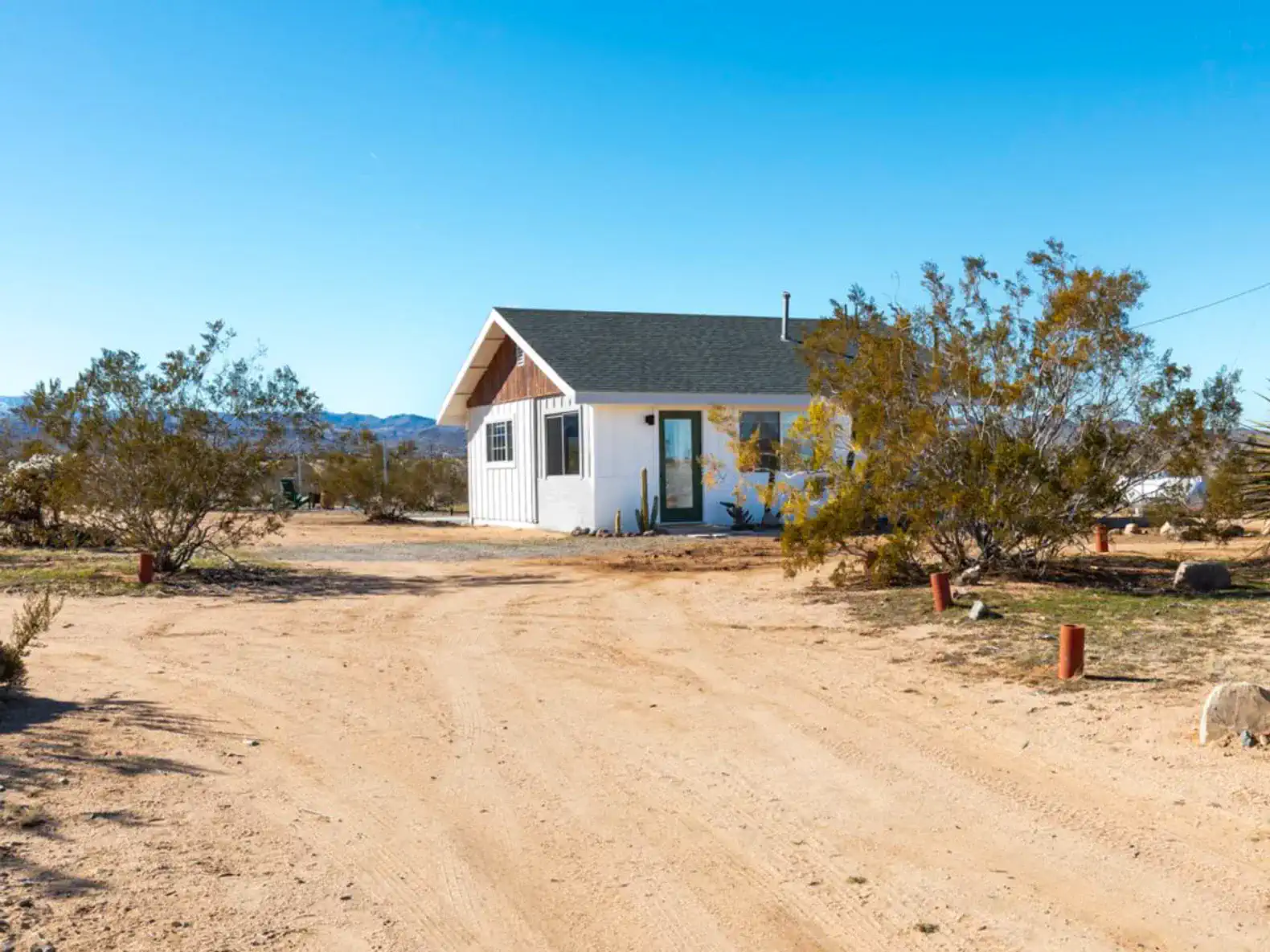 Charming desert home with a white exterior and surrounding vegetation