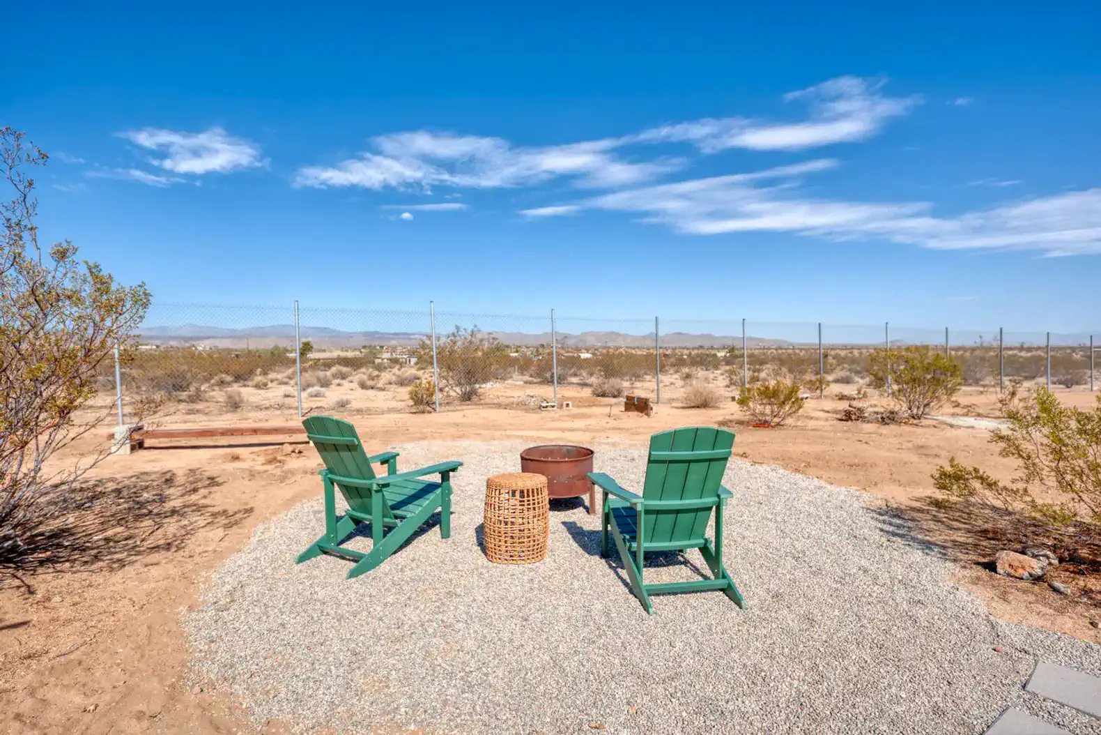 Cozy outdoor seating area with green chairs and fire pit surrounded by desert landscape