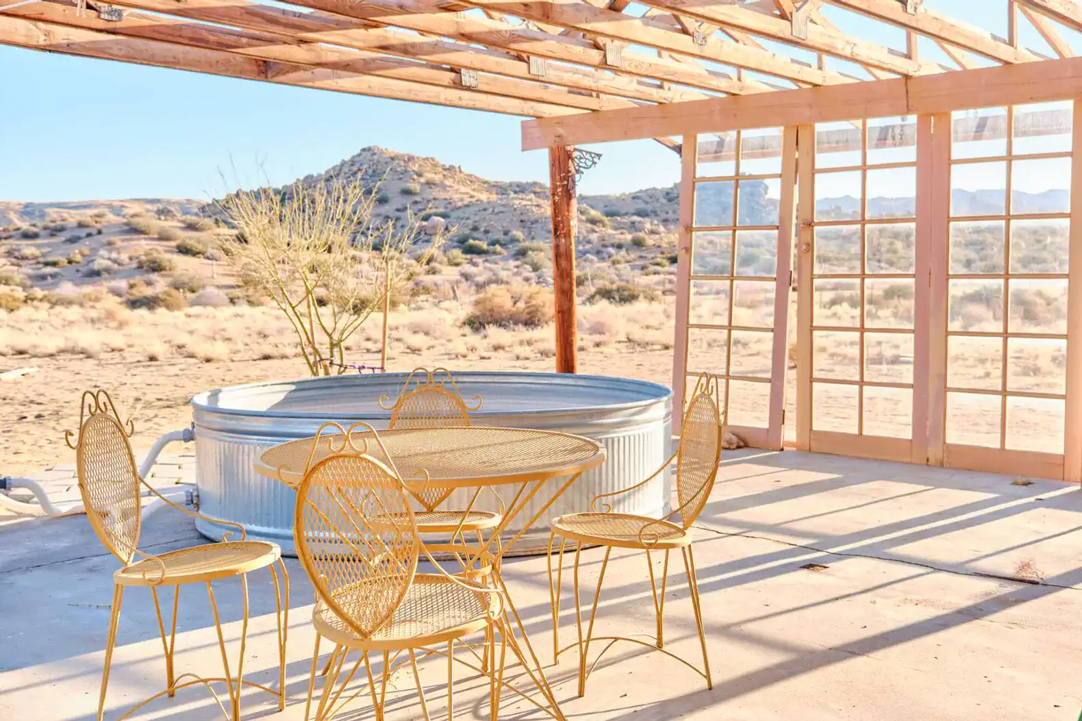 Outdoor seating area with a round table and chairs overlooking desert landscape
