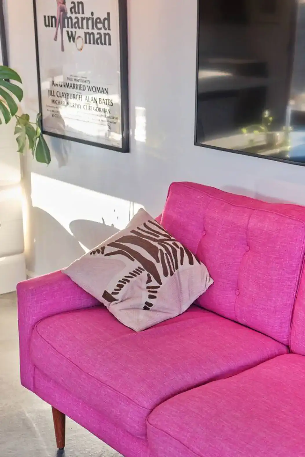Bright pink couch with a decorative pillow in a stylish living area