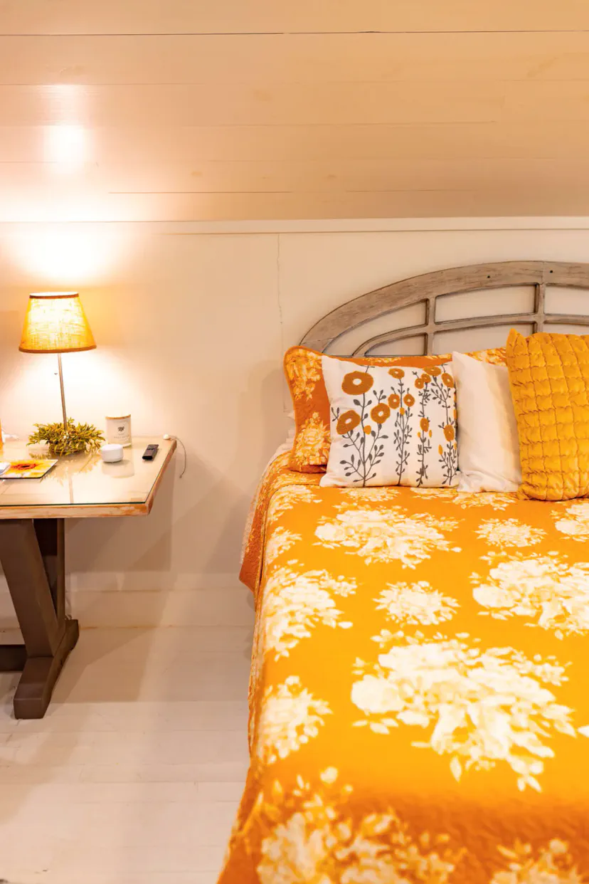 Cozy bedroom featuring a bright orange floral bedspread and bedside lamp